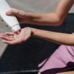 Kobieta nad basenem wyciska krem z filtrem SPF na dłoń