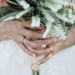 Panna młoda trzyma w dłoniach bukiet ślubny z widoczną obrączką