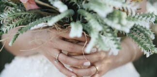 Jak wybrać idealny bukiet ślubny w zależności od pory roku i stylu wesela Panna młoda trzyma w dłoniach bukiet ślubny z widoczną obrączką