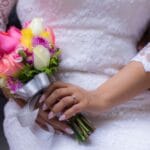 Panna młoda w koronkowej sukni trzyma kolorowy bukiet ślubny