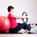 Kobieta w ciąży ćwiczy pilates z ringiem i piłką na siłowni
