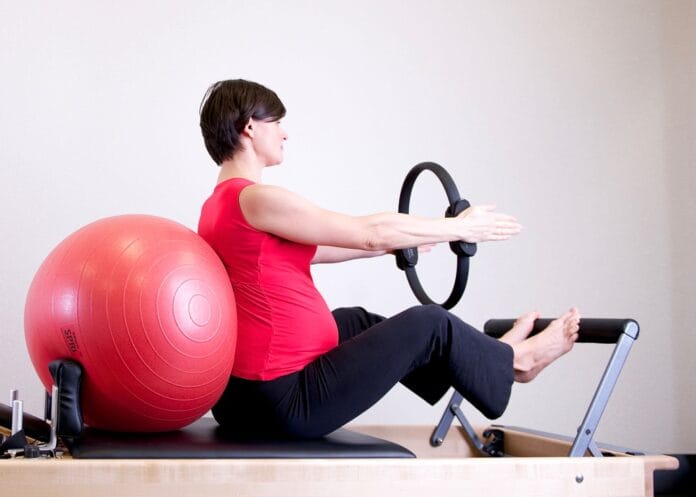Kobieta w ciąży ćwiczy pilates z ringiem i piłką na siłowni Kobieta w ciąży ćwiczy pilates z ringiem i piłką na siłowni