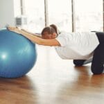 Kobieta w ciąży ćwiczy z piłką fitness na treningu w siłowni