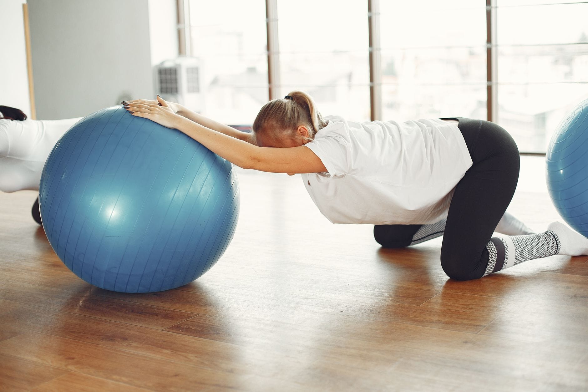 Kobieta w ciąży ćwiczy z piłką fitness na treningu w siłowni